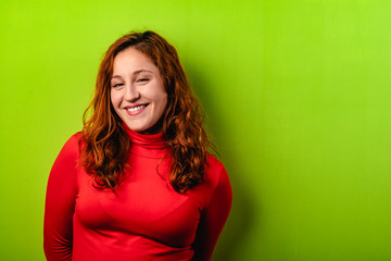 beautiful redhead girl with red shirt and green background. Copy space for text