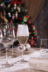 Champagne in a tall glass is on the table. Christmas tree out of focus. Flank. Macro photo in the interior.