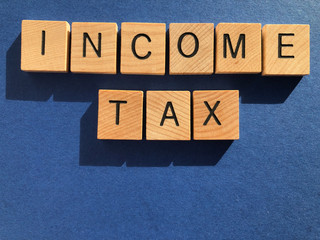 Income tax, word in 3d wooden alphabet letters on blue background