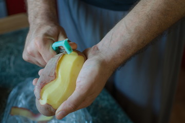 closeup of hands peeling a potato