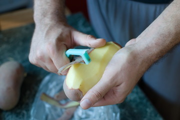 closeup of hands peeling a potato