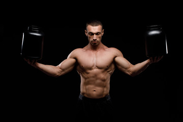 Muscular bodybuilder with jar of protein on a dark background. Sports nutrition. Bodybuilding...