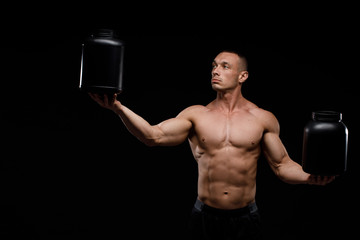 Muscular bodybuilder with jar of protein on a dark background. Sports nutrition. Bodybuilding nutrition supplements, sport, workout, healthy lifestyle concept.