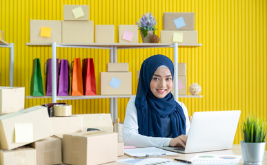 Young asian muslim woman in hijab dress is working at home typing on through laptop.. Small business owner and online marketing and SME concept.