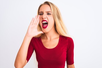 Young beautiful woman wearing red t-shirt standing over isolated white background shouting and screaming loud to side with hand on mouth. Communication concept.