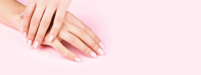 Gordijnen Vrouwelijke handen met klassieke pastel manicure op roze achtergrond. © Olga Zarytska
