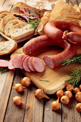 Smoked sausage with bread and spices on a old wooden table.