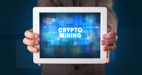 Young business person working on tablet and shows the inscription: CRYPTO MINING