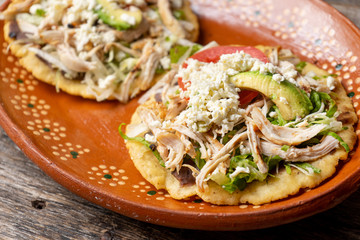 Yucatecan salbutes with chicken meat on wooden background