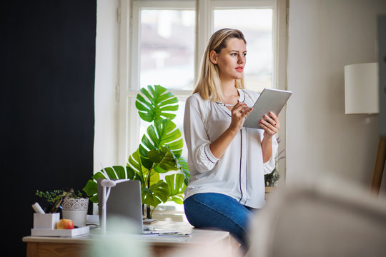 Young Woman With Tablet Indoors In Home Office, Working.