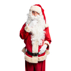 Middle age handsome man wearing Santa Claus costume and beard standing Looking fascinated with disbelief, surprise and amazed expression with hands on chin