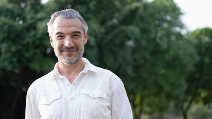 Portrait of middle aged man in the park and smiling. 