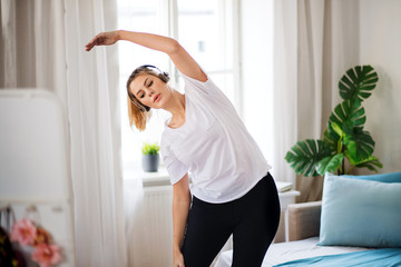 Young woman doing exercise in bedroom indoors at home.