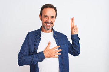 Middle age handsome man wearing blue denim shirt standing over isolated white background smiling swearing with hand on chest and fingers up, making a loyalty promise oath