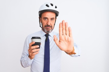 Middle age businessman wearing bike helmet drinking coffee over isolated white background with open hand doing stop sign with serious and confident expression, defense gesture