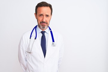 Middle age doctor man wearing coat and stethoscope standing over isolated white background depressed and worry for distress, crying angry and afraid. Sad expression.