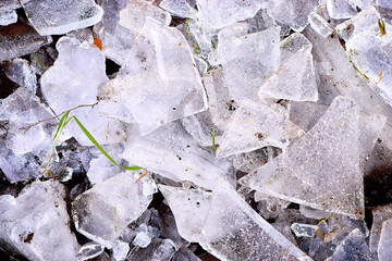 Ice fragments on frozen lake water level. The ice broken into shinning jagged pieces.