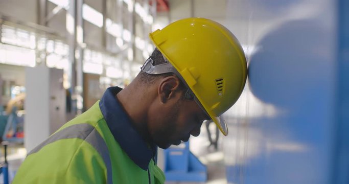 Black industry factory frustrated worker in helmet bangs his head against the wall. Negative upset person lost job has no money