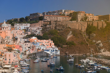 Fototapeta na wymiar Panoramic view of beautiful Procida on a sunny summer day. Colorful cafes, houses and restaurants, fishing boats and yachts, clear blue sky and the azure sea on the island of Procida, Italy. Napoli