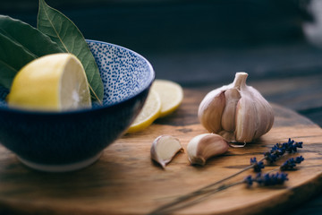 Still life with garlic and lemon in blue bowl on wooden cutting board