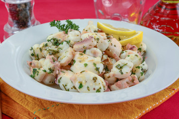 Octopus pieces cooked with garlic and parsley on a plate