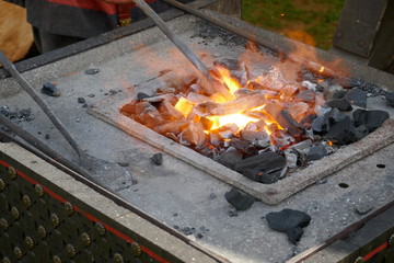 The forge. Blacksmith at work. He hits with the hammer on a glowing iron rod. Close-up