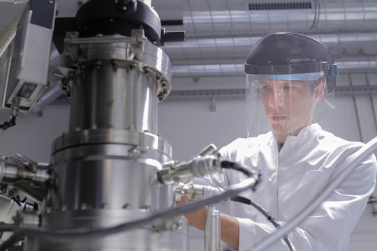 Scientist standing in analytical laboratory with scanning electron microscope and spectrometer