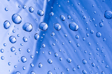Naklejka na ściany i meble Drops of water on a blue metal surface. Abstract blue background made of water drops. Selective focus.
