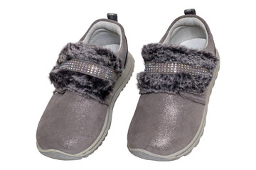 Child shoes fashion. Close-up of a pair beautiful gray silver suede sneaker or sports shoes for girls with fur and rhinestone decoration isolated on a white background. Macro of kids trendy footwear.