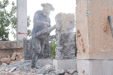 Obraz na płótnie Canvas Builder workers using pneumatic hammer drill equipment breaking concrete bridge pillars at road construction site.