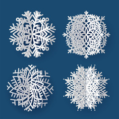 Set of white 3d volume paper snowflakes on dark blue background. Three-dimensional paper cur flakes of snow with shadows.