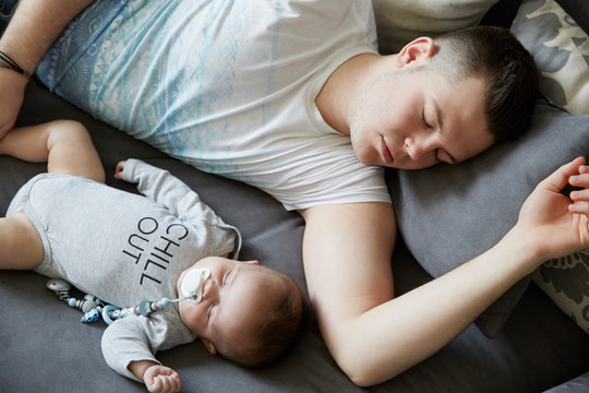 Young father and baby sleeping on couch