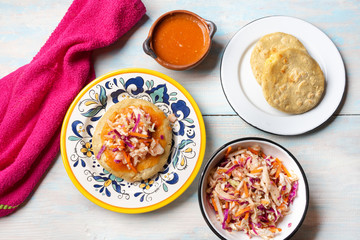 Salvadoran pupusas with coleslaw and tomato sauce on wooden background