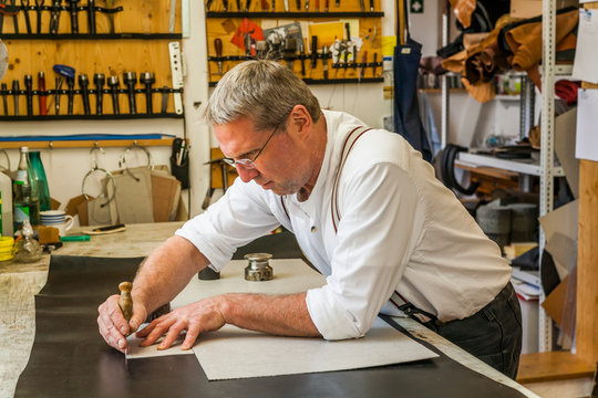 Saddler cutting piece of leather with stencil