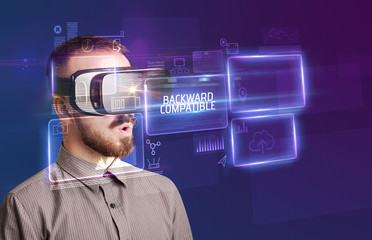 Businessman looking through Virtual Reality glasses with BACKWARD COMPATIBLE inscription, new technology concept