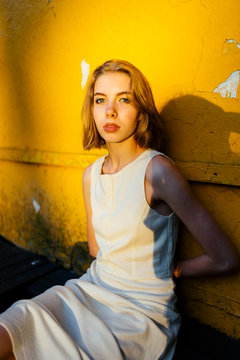 portrait of a woman sitting near a yellow texture wall