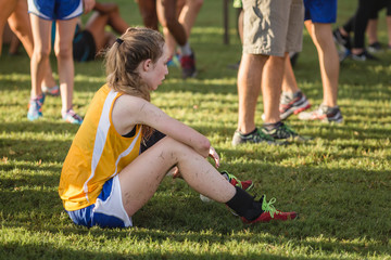 Teen Girl Cross Country Runner Rests Covered in Grass After Race