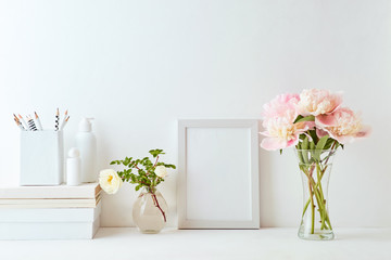 Home interior with decor elements. White frame, pink peonies in a vase, interior decoration