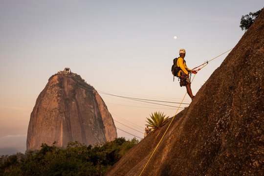 Man rappelling in Morro da Urca with Sugar Loaf Mountain on the back
