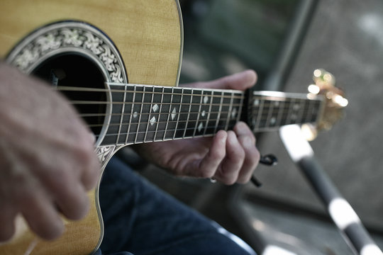 Close up of a pair of hands strumming a guitar