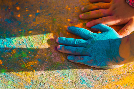 children's hands filled with coloured powders on the red floor