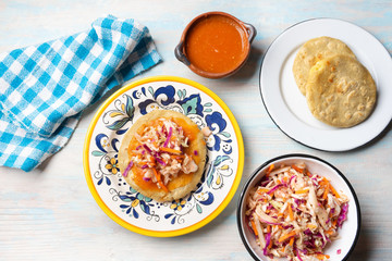 Salvadoran pupusas with coleslaw and tomato sauce on wooden background
