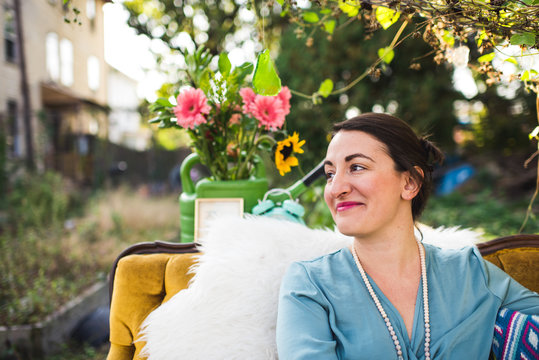 Smiling Woman Outdoors With Flowers On A Couch
