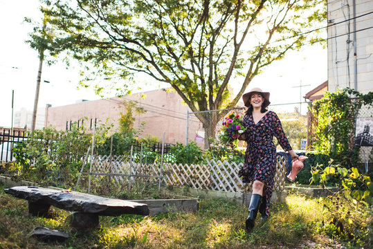 happy woman walking in urban garden with fresh flowers