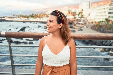 Beautiful young woman walking on beach promenade enjoying ocean view smiling happy on summer vacation