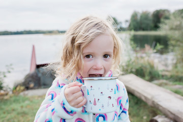 young girl laughing drinking hot chocolate whilst camping outdoors