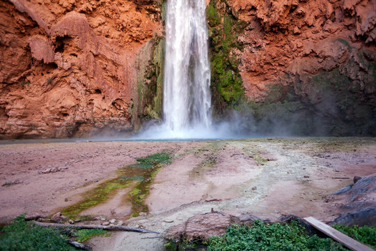 Bottom of a flowing waterfall hitting the ground and making mist