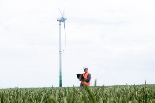 older energy engineer in front of a wind turbine