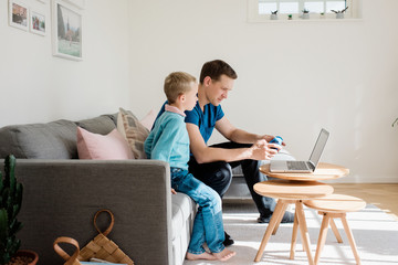 father and son looking at a laptop together at home