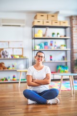 Young beautiful teacher wearing glasses sitting at kindergarten